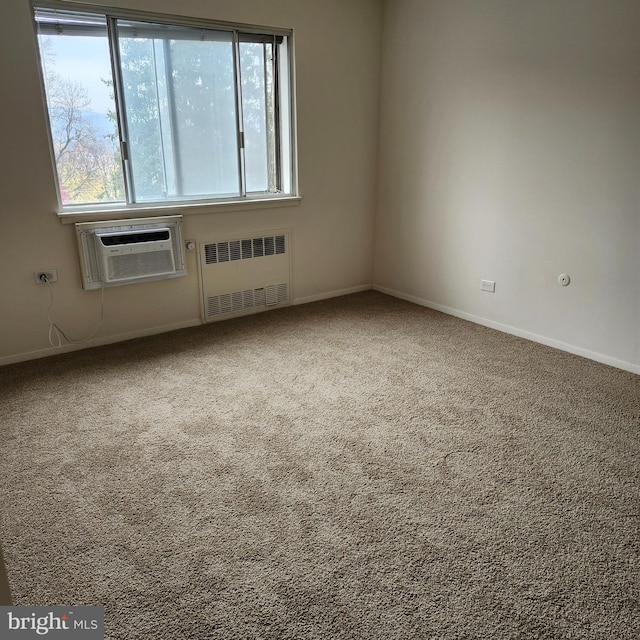 carpeted empty room featuring an AC wall unit, radiator, and plenty of natural light