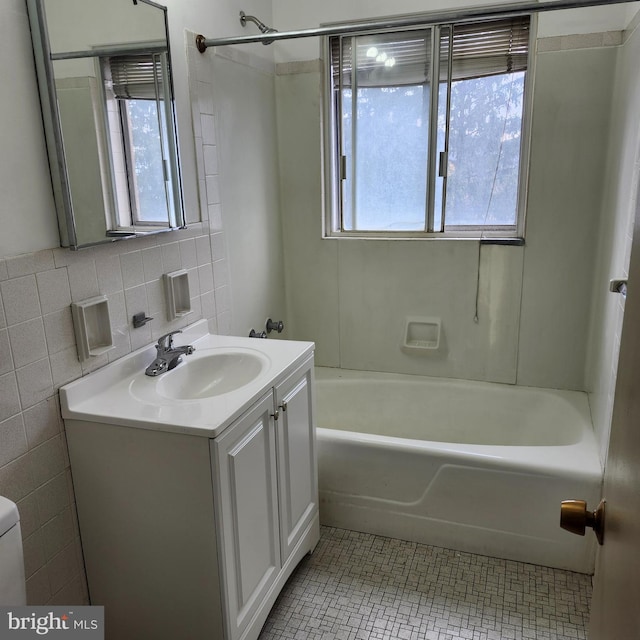 full bathroom featuring plenty of natural light, vanity, tile walls, and washtub / shower combination