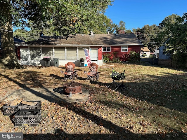 back of property with a lawn and a fire pit