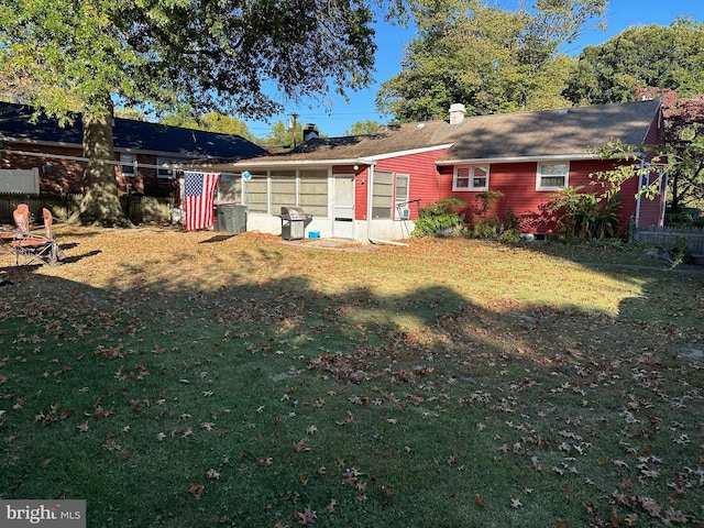 rear view of property with a lawn and a sunroom