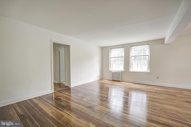 spare room featuring radiator and wood-type flooring