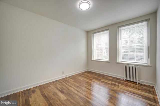 unfurnished room with radiator heating unit and dark wood-type flooring