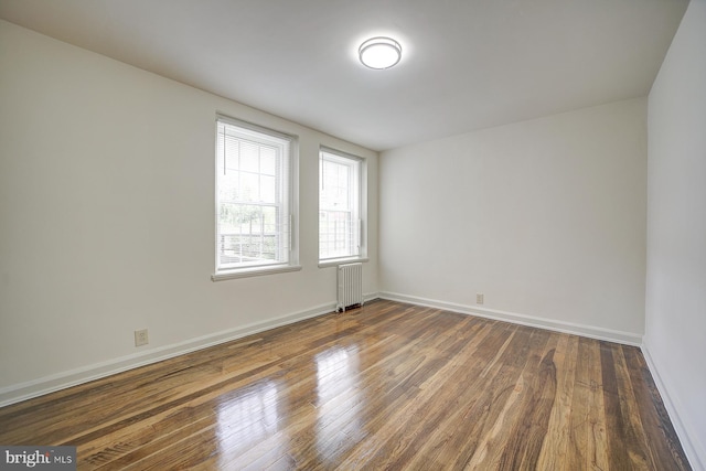 unfurnished room with dark hardwood / wood-style flooring and radiator heating unit