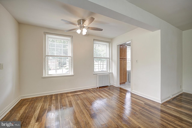 spare room with ceiling fan, dark wood-type flooring, and radiator