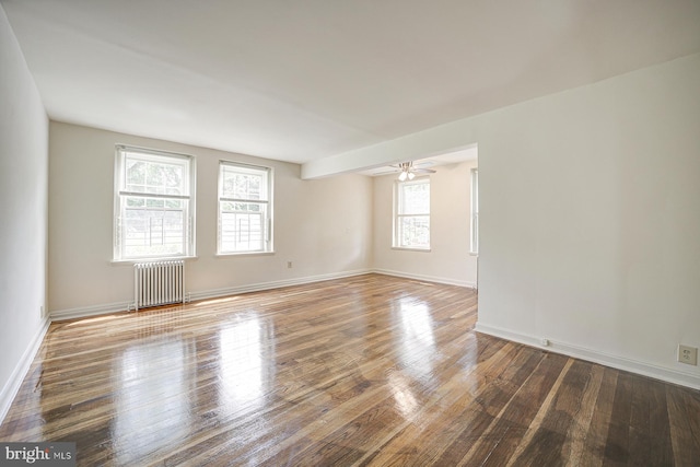 empty room featuring radiator, ceiling fan, plenty of natural light, and hardwood / wood-style floors