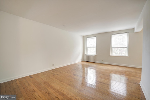 empty room with light hardwood / wood-style flooring and radiator