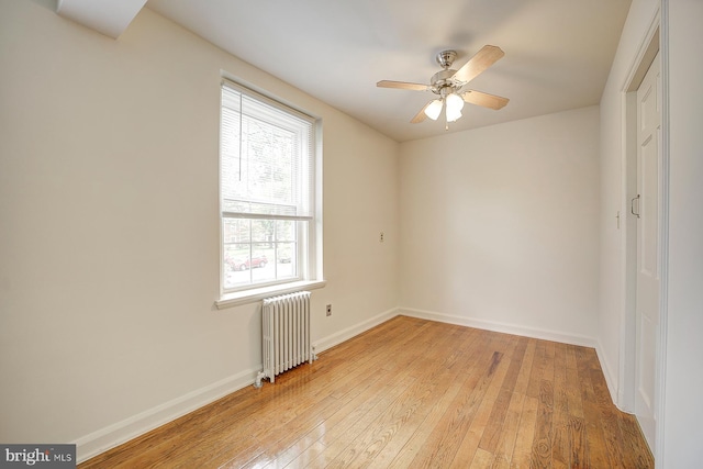 empty room featuring ceiling fan, light hardwood / wood-style floors, and radiator heating unit