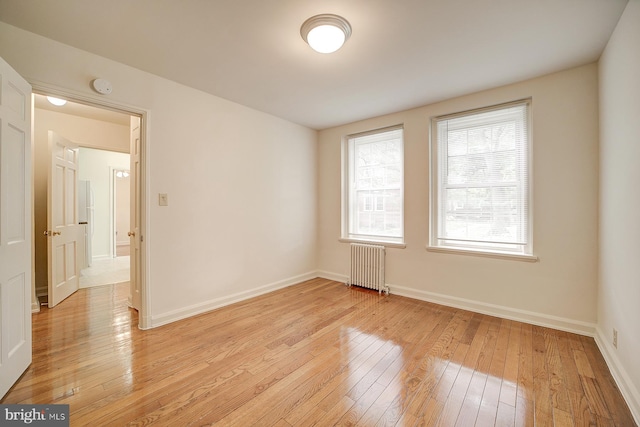 spare room with radiator heating unit and light hardwood / wood-style flooring