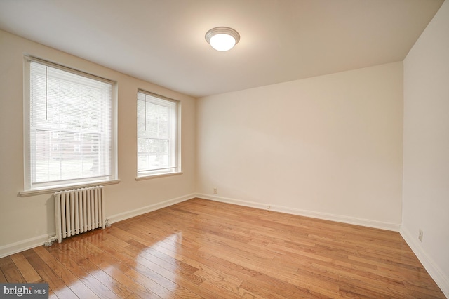 unfurnished room with a wealth of natural light, light hardwood / wood-style floors, and radiator