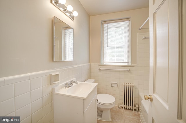 bathroom featuring radiator heating unit, tile patterned floors, toilet, vanity, and tile walls