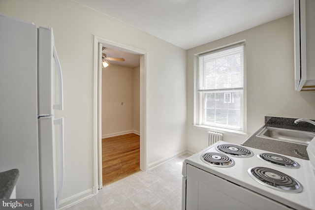 kitchen featuring sink, white refrigerator, radiator heating unit, light hardwood / wood-style floors, and range with electric stovetop