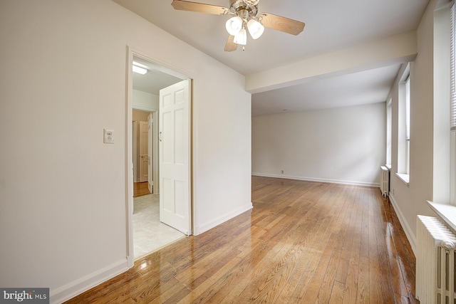 empty room with light hardwood / wood-style flooring, radiator, and ceiling fan