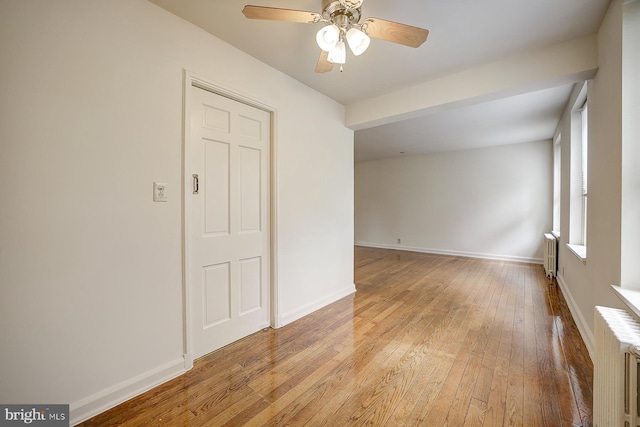 spare room with ceiling fan, light hardwood / wood-style floors, and radiator