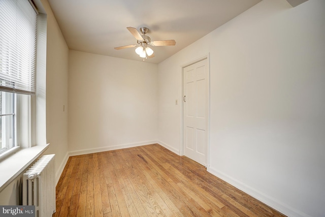 empty room with radiator, ceiling fan, and light hardwood / wood-style floors