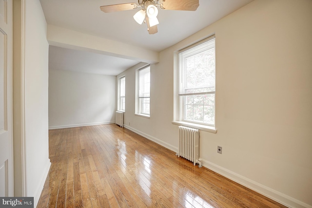 unfurnished room with radiator, ceiling fan, and light hardwood / wood-style flooring