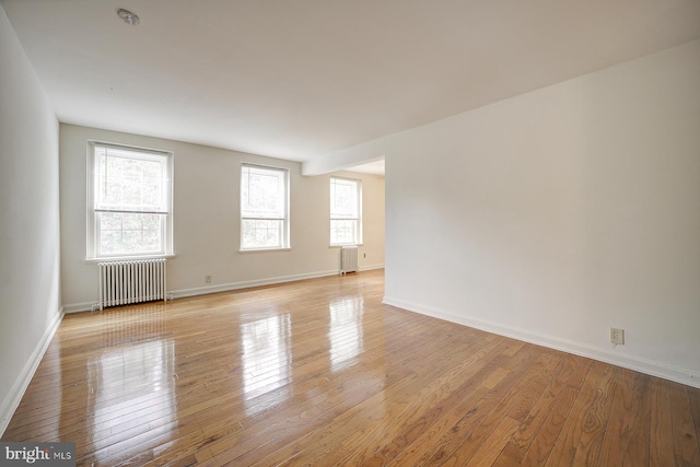 spare room featuring radiator and light hardwood / wood-style flooring