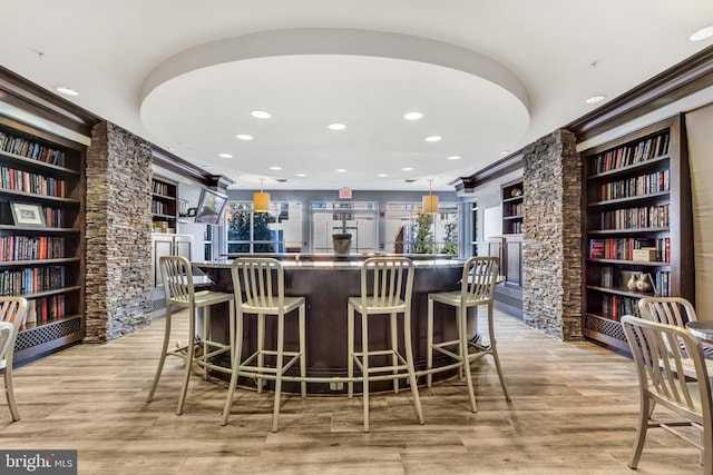 bar featuring decorative light fixtures, light hardwood / wood-style floors, and built in features