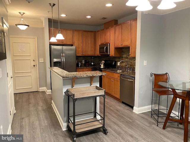 kitchen with a breakfast bar area, light hardwood / wood-style flooring, decorative light fixtures, and appliances with stainless steel finishes