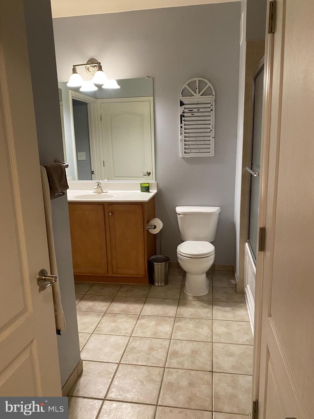 bathroom featuring tile patterned flooring, vanity, toilet, and a shower with door