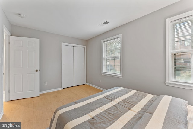 bedroom featuring a closet, light hardwood / wood-style floors, and multiple windows