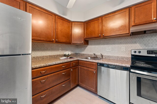 kitchen with appliances with stainless steel finishes, tasteful backsplash, exhaust hood, and sink