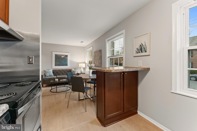 kitchen featuring kitchen peninsula, light hardwood / wood-style flooring, stainless steel range with electric cooktop, and exhaust hood