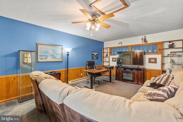 carpeted living room featuring a textured ceiling, a baseboard radiator, ceiling fan, and wooden walls