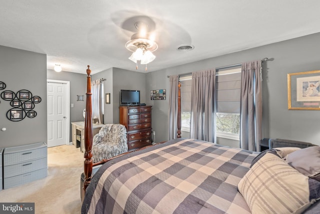 bedroom with ceiling fan, light colored carpet, and a textured ceiling