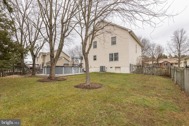 rear view of property featuring central AC unit and a lawn