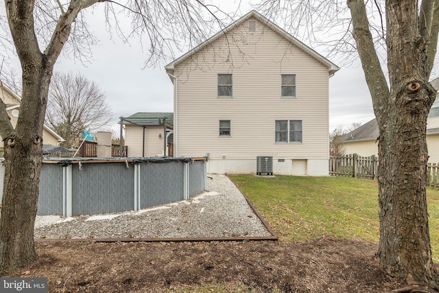 back of house featuring central AC unit, a covered pool, and a lawn