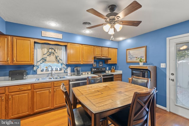 kitchen featuring ceiling fan, sink, a textured ceiling, appliances with stainless steel finishes, and light wood-type flooring