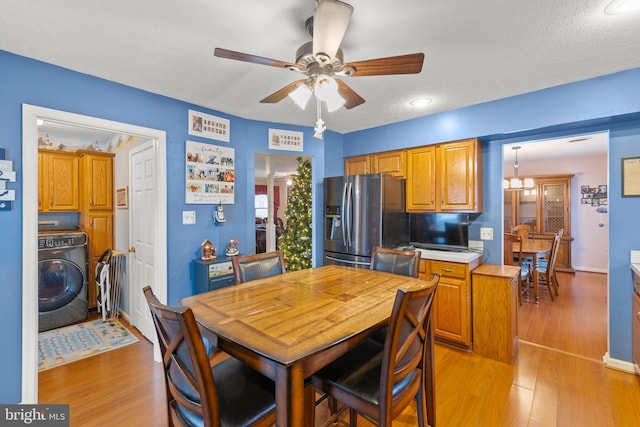 dining room with a textured ceiling, ceiling fan with notable chandelier, washer / clothes dryer, and light hardwood / wood-style floors