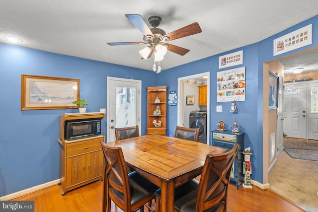 dining area featuring ceiling fan, light wood-type flooring, a textured ceiling, and washing machine and clothes dryer