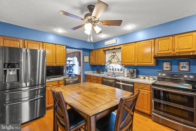 kitchen featuring ceiling fan, sink, light hardwood / wood-style flooring, a textured ceiling, and appliances with stainless steel finishes