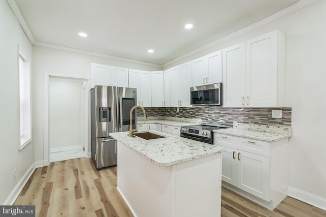 kitchen featuring appliances with stainless steel finishes, sink, white cabinets, light hardwood / wood-style floors, and an island with sink