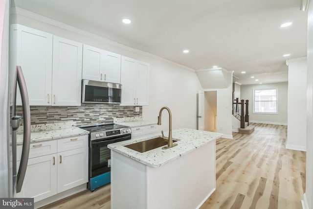 kitchen featuring sink, stainless steel appliances, an island with sink, light hardwood / wood-style floors, and white cabinets