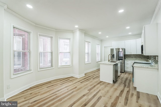 kitchen featuring light stone countertops, stainless steel appliances, a center island with sink, light hardwood / wood-style flooring, and white cabinets