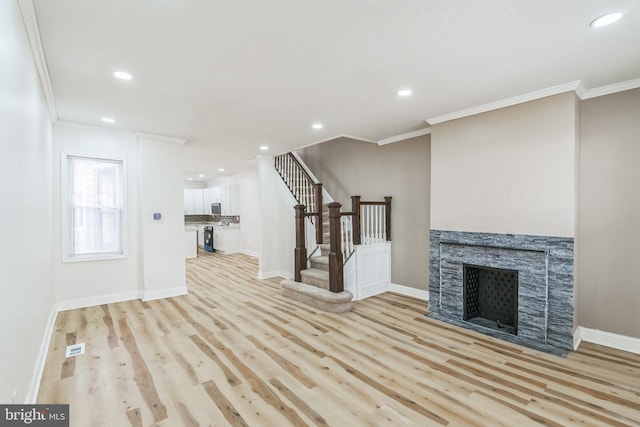 unfurnished living room featuring a fireplace, light wood-type flooring, and crown molding