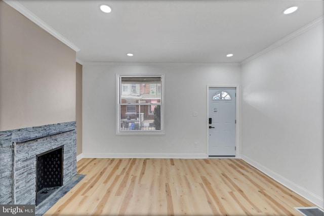 entryway with light hardwood / wood-style flooring, a stone fireplace, and crown molding