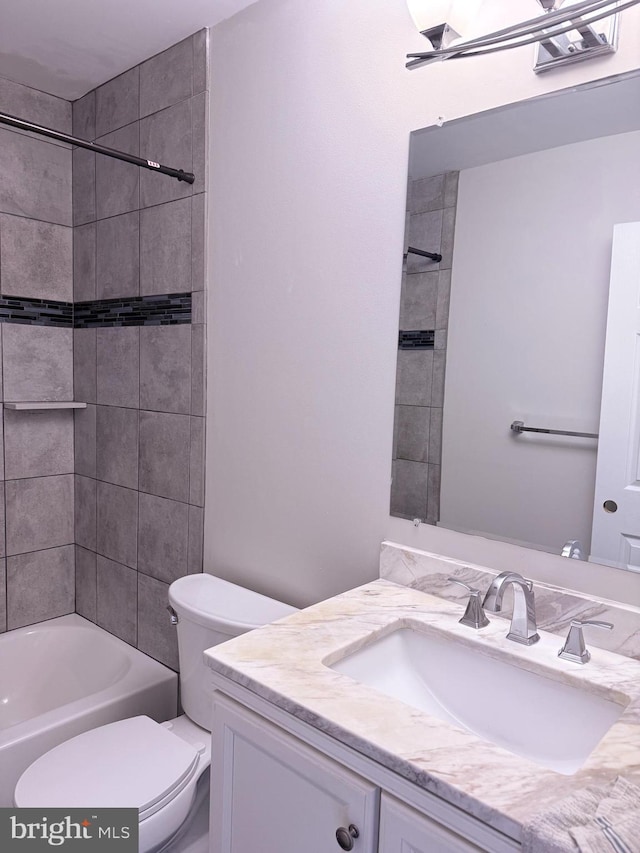 full bathroom featuring tiled shower / bath, vanity, and toilet