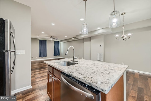 kitchen featuring stainless steel appliances, dark wood-type flooring, sink, decorative light fixtures, and an island with sink