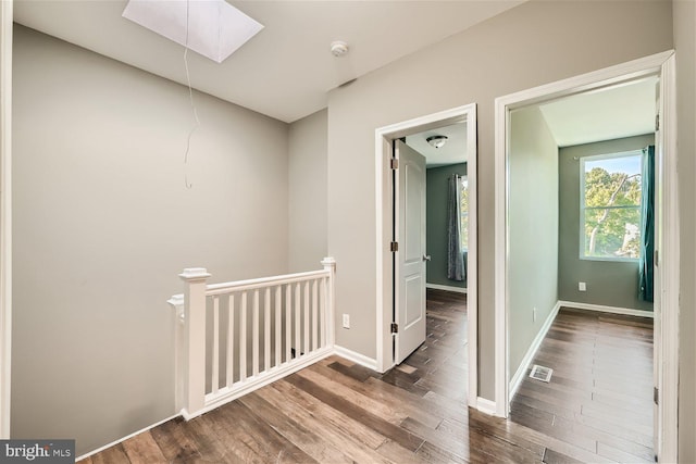 hallway featuring a skylight and hardwood / wood-style flooring