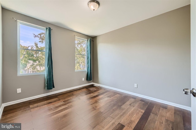 unfurnished room with dark wood-type flooring