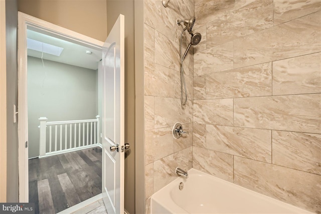 bathroom with wood-type flooring, tiled shower / bath combo, and a skylight