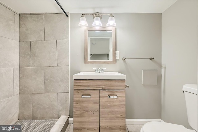 bathroom with a tile shower, vanity, and toilet