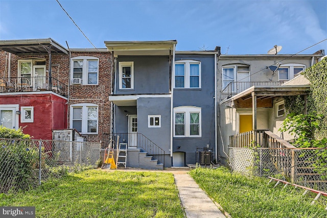 view of property featuring central air condition unit and a front yard