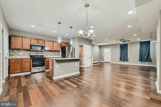 kitchen featuring ceiling fan with notable chandelier, stainless steel appliances, hanging light fixtures, and dark wood-type flooring