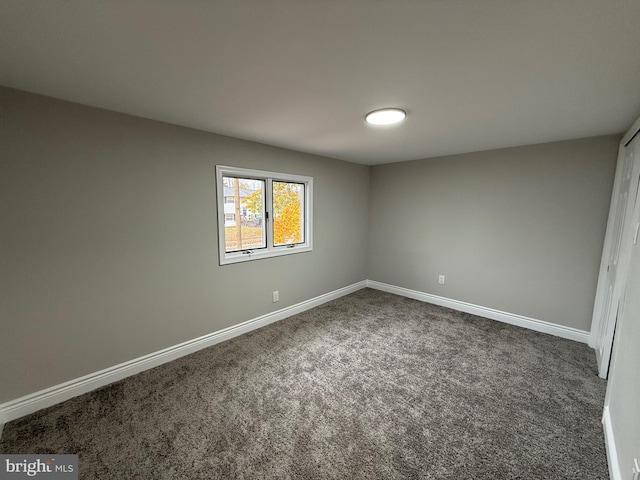 spare room featuring dark colored carpet