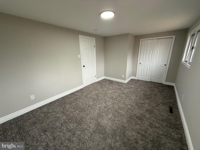 unfurnished bedroom with a closet and dark colored carpet