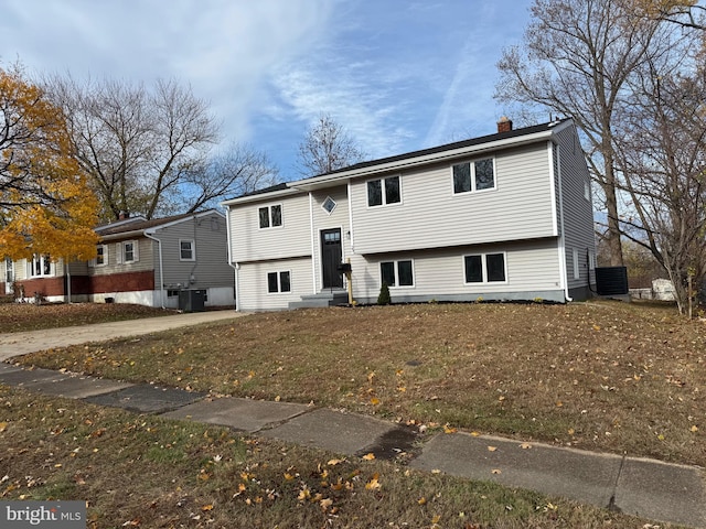 split foyer home with central AC unit and a front lawn